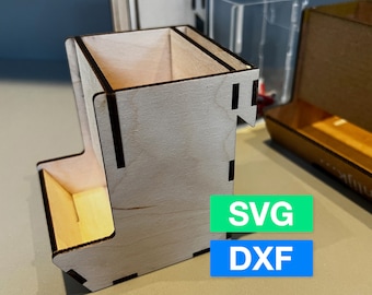 May include: A wooden dice tower with a compartment for dice. The tower is made of light wood with dark brown accents. The tower is sitting on a light brown surface. The image also includes the text "SVG" and "DXF".