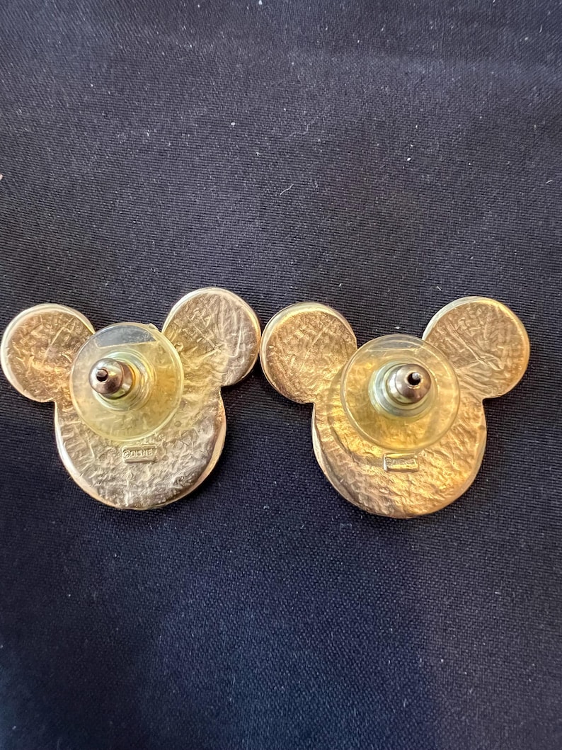 Pu&ograve; includere: Un paio di orecchini a bottone di Topolino dorati. Gli orecchini hanno la forma della testa di Topolino, con un viso rotondo e due orecchie rotonde. I retro hanno un perno e un supporto in plastica.