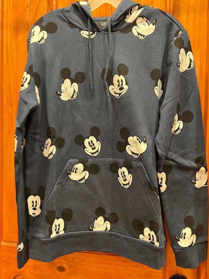 Pu&ograve; includere: Una felpa con cappuccio blu navy con un motivo ripetitivo di volti di Topolino.