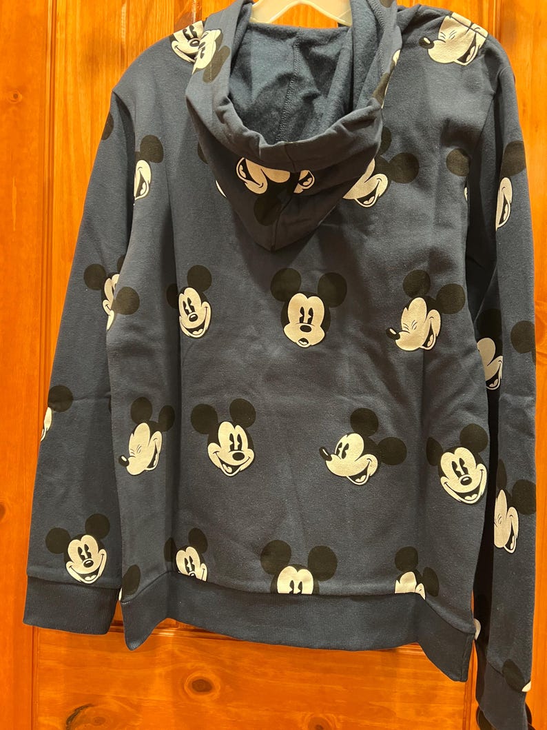 Pu&ograve; includere: Una felpa con cappuccio blu navy con un motivo ripetitivo di volti di Topolino.