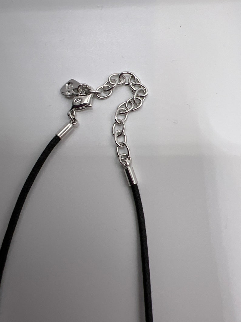 Puede incluir: Un collar de cord&oacute;n negro con un cierre y un extensor de cadena plateados.