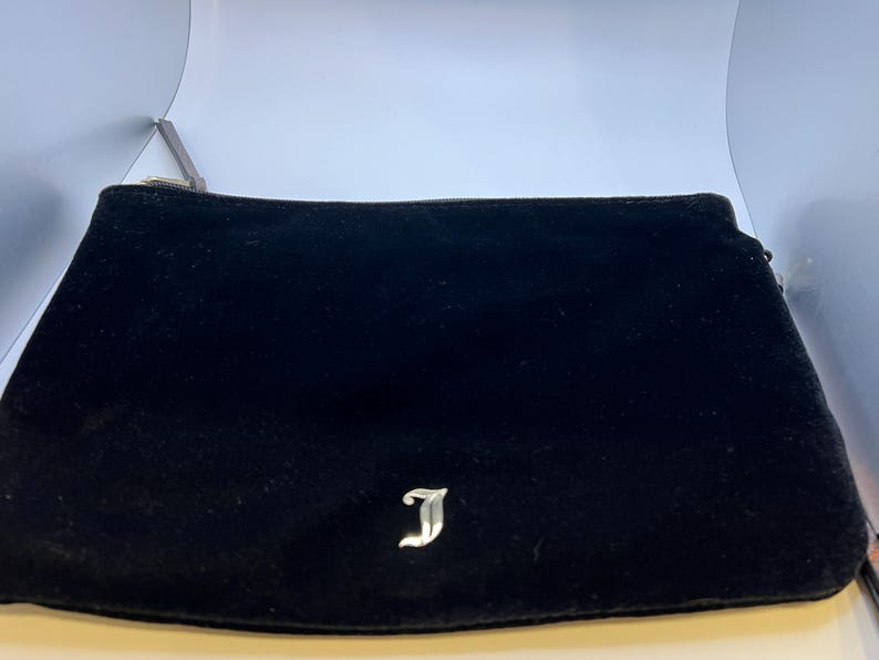 May include: Black velvet clutch with a silver J logo.