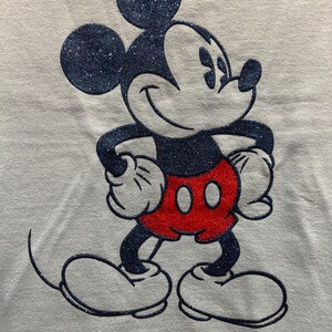 May include: A white t-shirt with a black and red glitter Mickey Mouse design.
