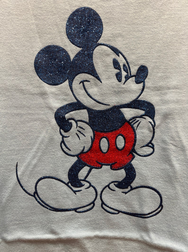 May include: A white t-shirt with a black and red glitter Mickey Mouse design.