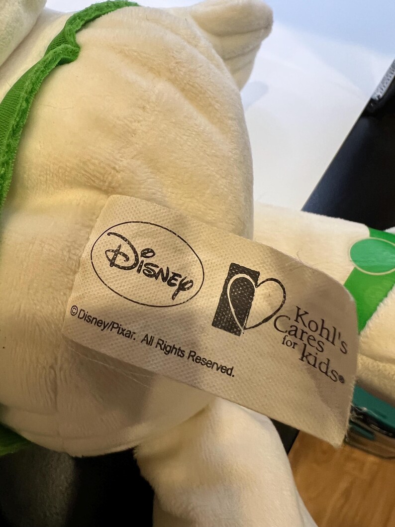 May include: White plush toy with green accents. The toy has a tag that reads "Disney/Pixar. All Rights Reserved." and a Kohl's Cares for Kids logo.