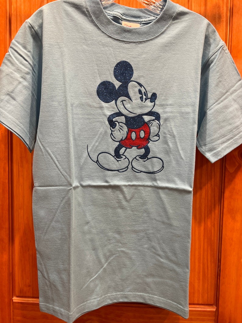 May include: A light blue t-shirt with a glittery blue and red Mickey Mouse graphic.
