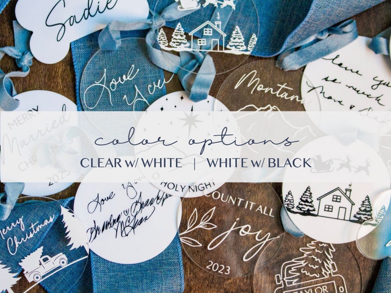 May include: A selection of clear and white round acrylic baubles featuring various Christmas-themed designs and text, such as "Merry Christmas", "Love You", "Count It All Joy", and "Holy Night". The baubles are arranged on a wooden surface with blue ribbon.