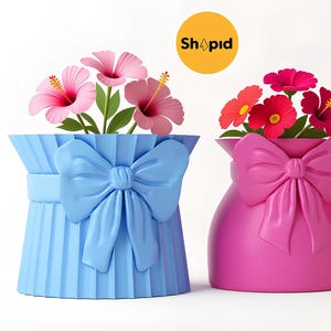 Peut inclure: Trois vases colorés avec des nœuds, chacun contenant des fleurs vibrantes. Les vases sont bleus, roses et rouges, avec des hibiscus roses, des fleurs rouges et oranges et des roses roses. Le logo Shopid est en arrière-plan.