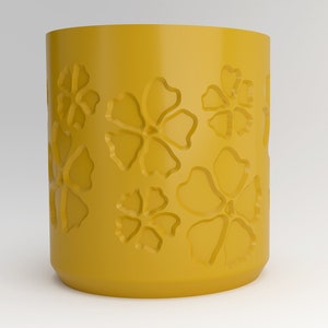 May include: A yellow ceramic mug with a floral design. The mug has a smooth, rounded shape and is decorated with raised flower patterns.