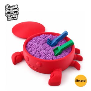 May include: A red crab-shaped container filled with purple kinetic sand, featuring a detached red lid, a blue plastic rake, and a green plastic shovel. The text "Digital product with Commercial license included" and "Shapid" are visible.