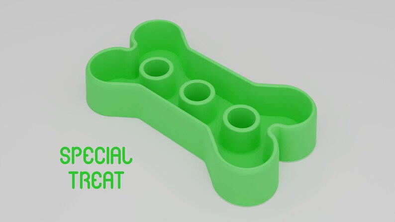 May include: Green plastic bone-shaped dog treat dispenser with three holes. The dispenser has the words "SPECIAL TREAT" printed on the front.