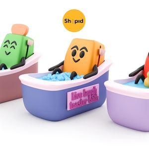 Può includere: Tre tostapane dei cartoni animati che si rilassano nelle vasche da bagno. I tostapane sono verdi, arancioni e rossi, ognuno con un'espressione diversa. Le vasche da bagno sono rosa, blu e viola, con la scritta "Live laugh toaster bath" su una. Un'anatra gialla galleggia in una vasca.