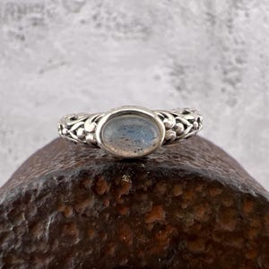 May include: A silver ring with a delicate floral design and a light blue oval gemstone.