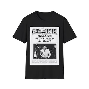 Op de afbeelding: Zwart T-shirt met een vintage krantenprint met een foto van een man die pool speelt. De kop luidt "MORALES STUNS FIELD AT RED'S".
