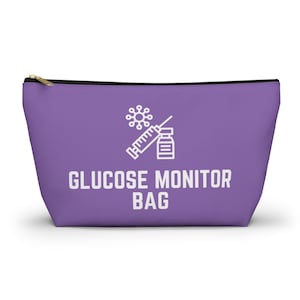 Puede incluir: Una bolsa con cremallera de color lavanda con las palabras "GLUCOSE MONITOR BAG" en letras blancas. Encima del texto hay un gráfico blanco de una jeringa, un vial y una molécula estilizada. La bolsa tiene una cremallera dorada.