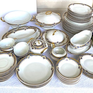 Puede incluir: Un juego de vajilla de porcelana vintage con un patr&oacute;n floral azul y dorado. El juego incluye platos, cuencos, una fuente para servir, una salsera y un azucarero.