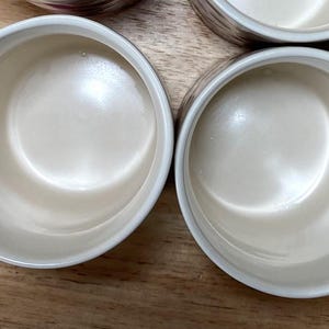 May include: Four white ceramic mugs with a handle on the side. The mugs are empty and have a smooth, glossy finish.