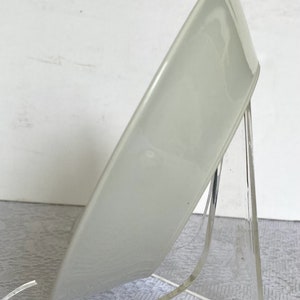 Puede incluir: Un cuenco de cer&aacute;mica blanca con un acabado liso y brillante. El cuenco se muestra en un soporte de acr&iacute;lico transparente.