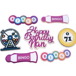 Puede incluir: Un conjunto de decoraciones de fiesta de bingo de color rosa y blanco con las palabras "Happy Birthday Man" en purpurina rosa, una jaula de bingo y bolas de bingo con los números 71 y B, I, N, G, O.
