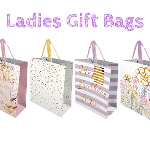 Puede incluir: Cuatro bolsas de regalo con diferentes diseños. Las bolsas son todas blancas con asas moradas y detalles en dorado. Los diseños incluyen un patrón de mármol con el texto "Let's Celebrate You!" un patrón de confeti, un patrón a rayas con el texto "Happy Birthday to You!" y un patrón floral.