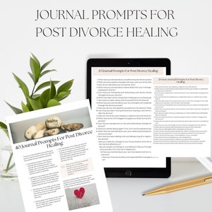 May include: A close-up of two pages of journal prompts for post-divorce healing. The pages are printed on white paper and feature a light blue background with a dark blue border. The text is in black and white. The top page has the title "40 Journal Prompts For Post Divorce Healing" and the bottom page has the title "20 Journal Prompts For Post Divorce Healing".
