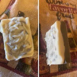 May include: Two bars of handmade soap. One bar is white with gray swirls and the other bar is white with gray swirls and a dark gray stripe.