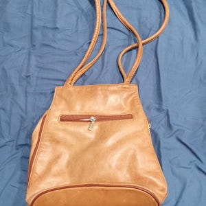 May include: A brown leather shoulder bag with a zippered pocket and a gold zipper pull.