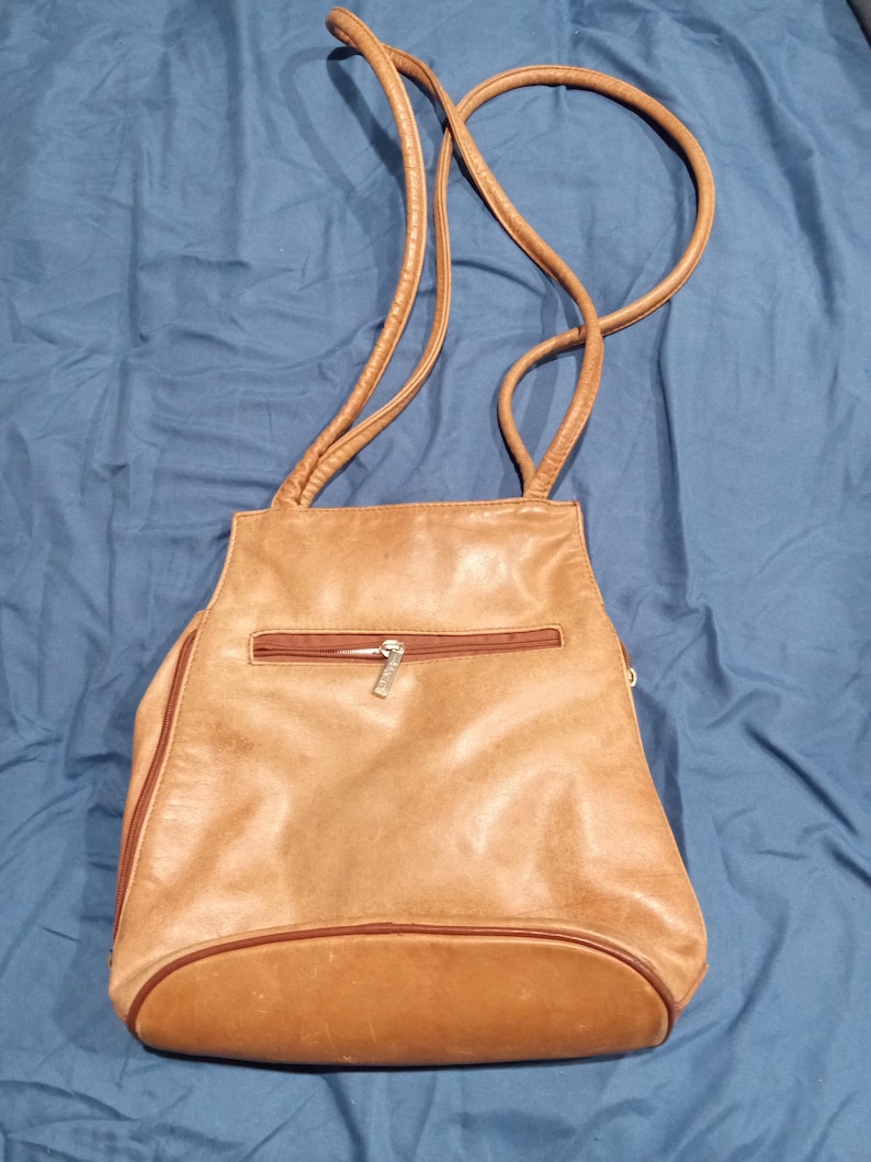 May include: A brown leather shoulder bag with a zippered pocket and a gold zipper pull.