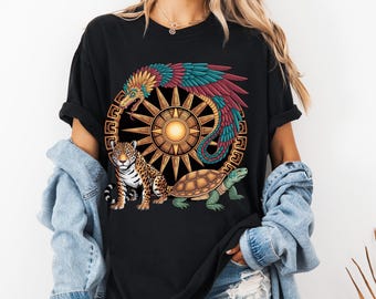 May include: Black t-shirt featuring a colorful Aztec-inspired design. The graphic includes a sun, a serpent, a jaguar, and a turtle. The serpent has red, teal, and yellow feathers. The jaguar has a spotted coat. The turtle is green.
