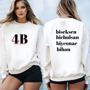 May include: White sweatshirt with the number "4B" printed on the front in black with a pink outline. The back of the sweatshirt has the words "bisekseu bichulsan biyeonae bihon" printed in black.
