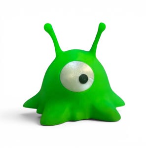 May include: A bright green, cartoonish alien figure with a single large eye and two antennae. The eye is white with a black pupil. The alien has a rounded body with four small, pointed appendages.