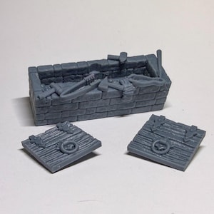 May include: A gray miniature treasure chest with a brick-like exterior, containing small tools and two separate wooden-style lids with ring handles. The chest is designed for tabletop gaming or model building.