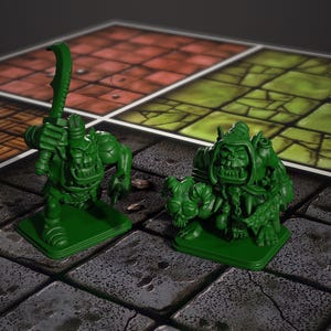 Könnte beinhalten: Zwei grüne Ork-Figuren auf einem Spielbrett. Ein Ork hält ein gebogenes Schwert, der andere hockt über einer gehörnten Kreatur. Das Spielbrett hat ein Steinplattenmuster und rote und grüne Quadrate.