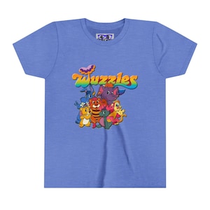 Könnte beinhalten: Hellblaues T-Shirt mit einem farbenfrohen Aufdruck des Wortes "Wuzzles" über einer Gruppe von Zeichentierfiguren. Das Design umfasst einen Bären, einen Elefanten, einen Löwen und andere Kreaturen in leuchtenden Farben. Das T-Shirt hat einen Rundhalsausschnitt.