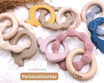 Puede incluir: Una colección de mordedores de silicona y madera de colores para bebés. Los mordedores tienen forma de anillo y diferentes texturas. Los mordedores de madera están grabados con las palabras "Minlala Kids" y "Linisa".