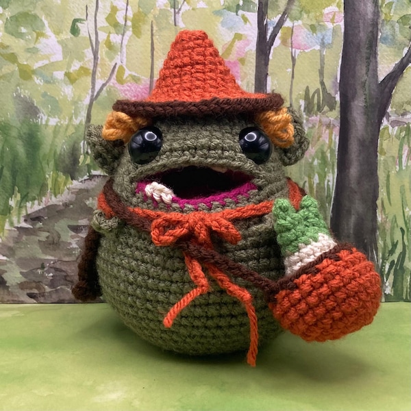David the Goblin, a crochet plush goblin with a leek in a satchel, a pointy hat and a stylish cape