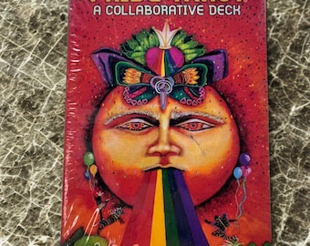 May include: A deck of Pride Tarot cards. The card box is red with the words "PRIDE TAROT" and "A COLLABORATIVE DECK". The artwork features a face with a rainbow emanating from the mouth. Colorful balloons and swirls are also present.