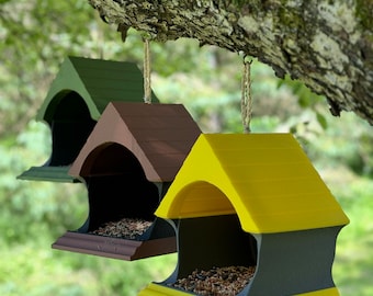 May include: Three bird feeders hanging from a tree branch. The feeders are made of wood and painted in different colors: green, brown, and yellow. Each feeder has a black roof and a small opening for birds to access the seed.
