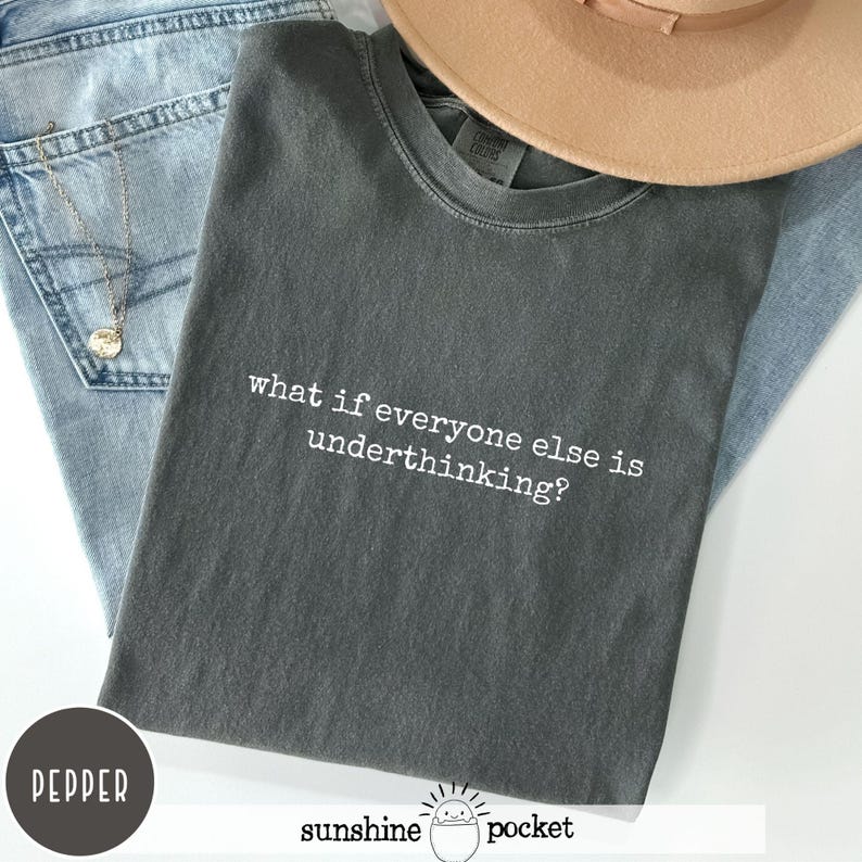 Peut inclure: Un t-shirt &agrave; col rond gris anthracite avec le texte blanc "what if everyone else is underthinking?" imprim&eacute; sur le devant. Le v&ecirc;tement pr&eacute;sente une coupe standard &agrave; manches courtes, affichant un style d&eacute;contract&eacute; avec une police claire.