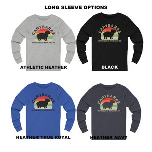 Pu&ograve; includere: Quattro t-shirt a maniche lunghe con una grafica di capibara e il testo "CAPYBARAS PROVING WESTLEY WRONG SINCE 1987". Le magliette sono disponibili in grigio melange atletico, nero, blu reale melange e blu navy melange.