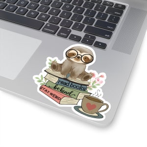 May include: A sticker featuring a cartoon sloth wearing glasses and sitting on a stack of books. The books have the text "read books be kind" and "STAY WEIRD". There is a cup of coffee with a heart on it next to the sloth.