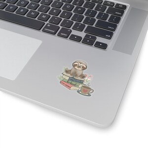 May include: A cute sloth wearing glasses sits on a stack of books with a cup of coffee. The books have the text "read books be kind" and "STAY WEIRD" on them.