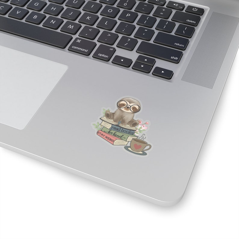 May include: A cute sloth wearing glasses sits on a stack of books with a cup of coffee. The books have the text "read books be kind" and "STAY WEIRD" on them.