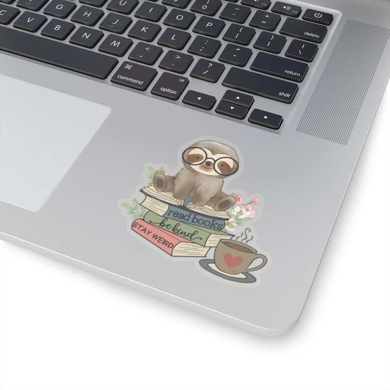 May include: A cute sloth wearing glasses sits on a stack of books. The books have the text "read books be kind" and "STAY WEIRD". A cup of coffee with a heart on it sits next to the books.