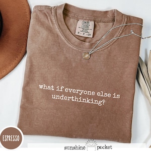 Peut inclure: Un t-shirt marron &agrave; manches courtes avec un col rond et le texte blanc what if everyone else is underthinking? imprim&eacute; sur le devant. Le t-shirt pr&eacute;sente une &eacute;tiquette de marque Comfort Colors au col int&eacute;rieur et est accompagn&eacute; d'un collier argent&eacute;.
