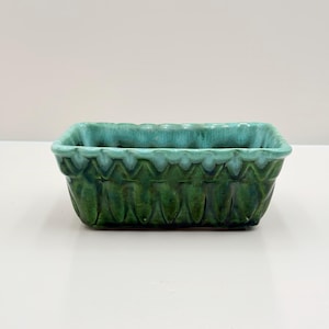 May include: A rectangular ceramic planter featuring a deep forest green base that transitions into a lighter turquoise glaze along the scalloped upper rim. The exterior surface displays a vertical ribbed texture with a glossy finish throughout.