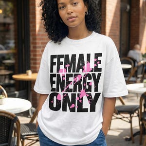 Women graphic tee design “Female Energy Only” in bold distressed typography with pink accents for modern streetwear looks