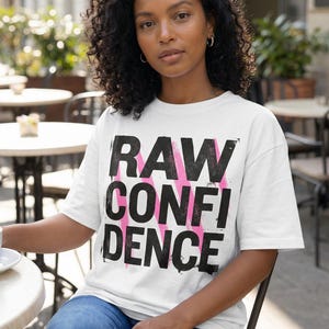 Women’s graphic t-shirt design “Raw Confidence” in bold distressed typography for modern streetwear style outfits