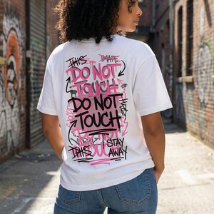 Women streetwear typography design “Noise Control” in distressed black letters with pink accent line on white graphic tee