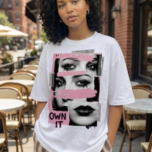 Women’s “Own It” face collage t-shirt design with pink brush stroke overlays and edgy streetwear aesthetic on white tee